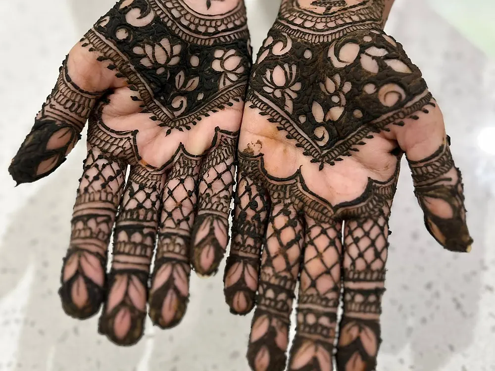 Bridal henna by Elite Threading on both palms: lotus flowers, lattice and leaf patterns to the fingertips